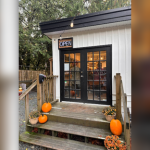 A cafe entrance featuring a welcoming door and a charming porch, surrounded by a serene outdoor setting.